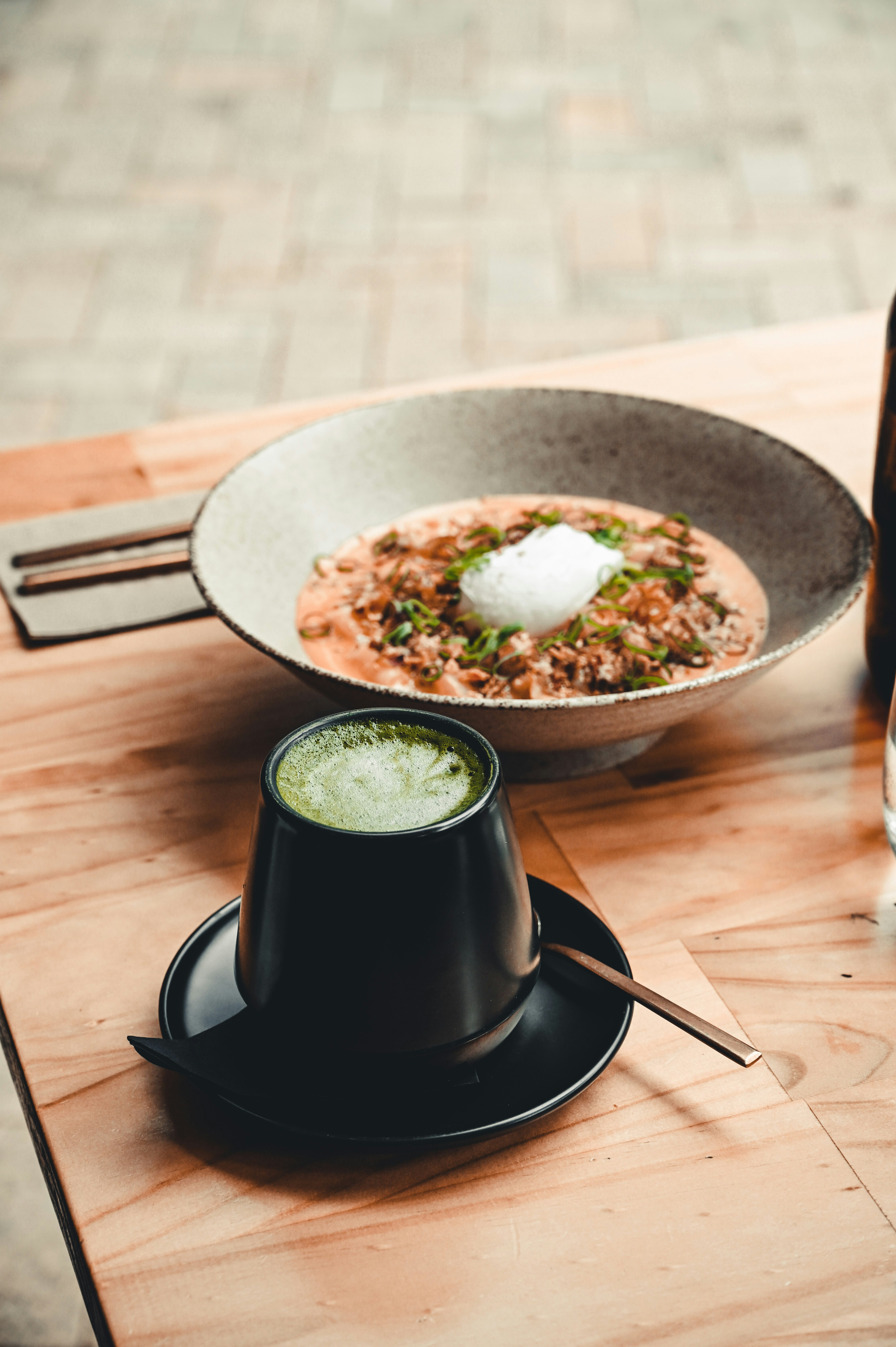 black ceramic mug on brown wooden round plate beside stainless steel fork